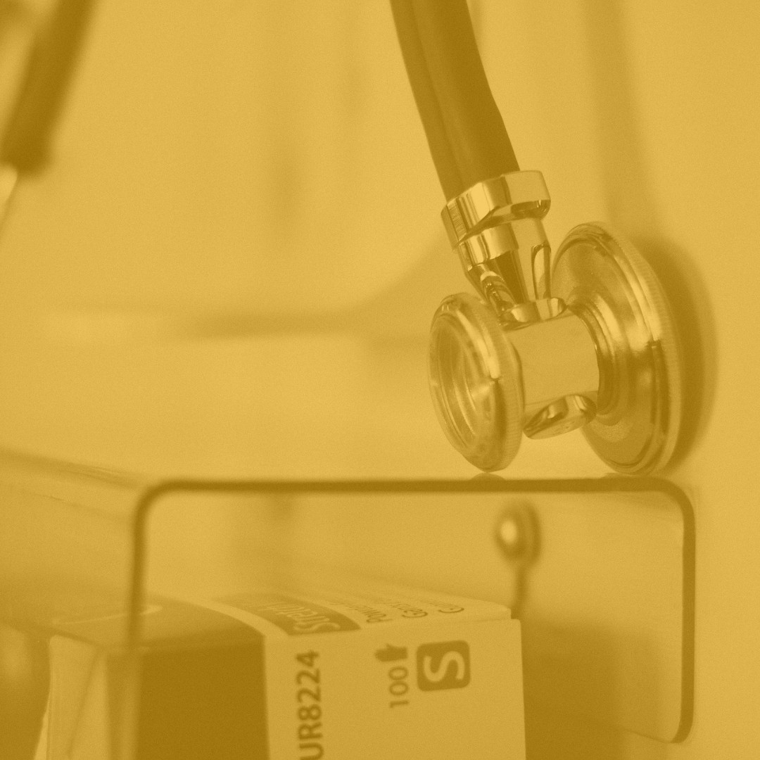 Estetoscópio metálico pendurado numa prateleira de consultório médico, simbolizando saúde, medicina e cuidados médicos.